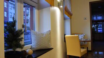 A cozy room with a window, a small plant, a patterned pillow, and a chair.