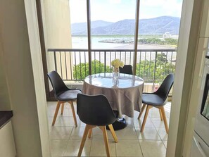 Enjoy a meal for four at the round table in front of a scenic view of a body of water and distant mountains.