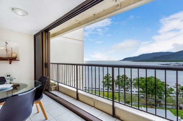 Enjoy a view of the water and distant mountains from the balcony with a glass table and chairs.