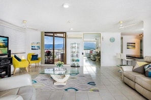 Relax in this stylish living room with a sofa, armchairs, and a large coffee table, offering a view of the surrounding landscape from the adjacent balcony.