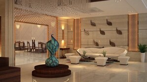 Un vestíbulo moderno con un sofá blanco, una escultura decorativa y un comedor al fondo.