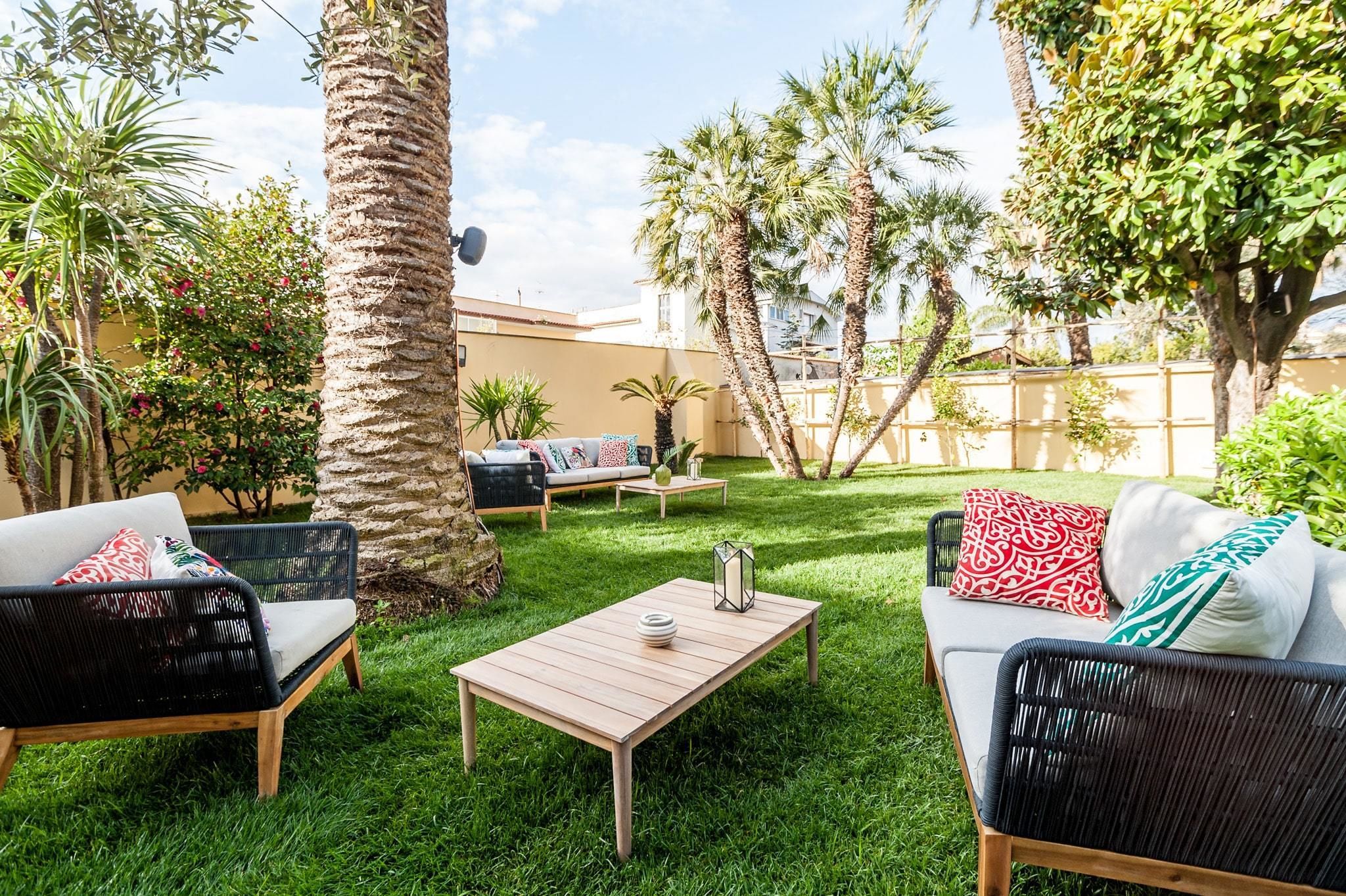 A patio with outdoor furniture, a table, and a variety of plants.