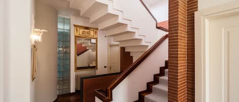 A staircase with wooden steps and a brick column, leading to a white door.