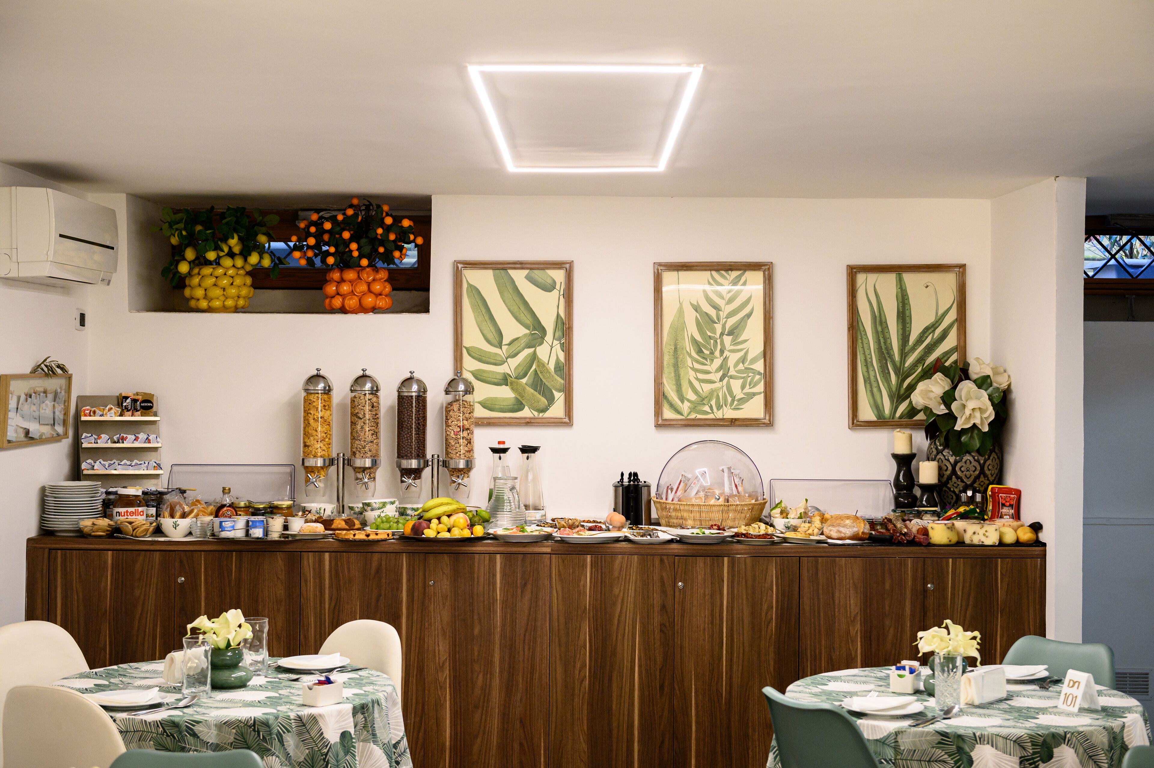 Un buffet de petit-déjeuner proposant une variété d’aliments, un coin café et des œuvres d’art décoratives sur les murs.