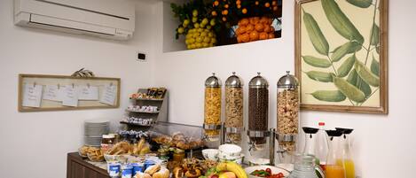 A buffet with a variety of food items, including fruits, pastries, and beverages.