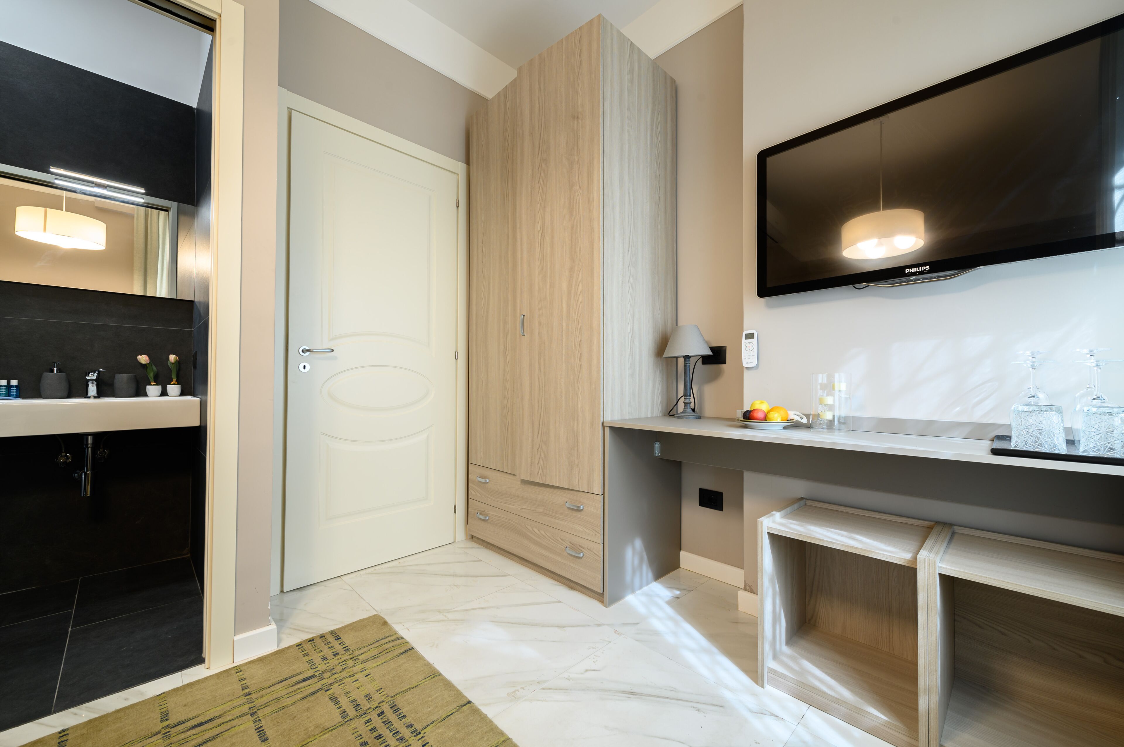 A modern kitchen with a built-in oven, a large flat-screen TV, and a wooden cabinet.