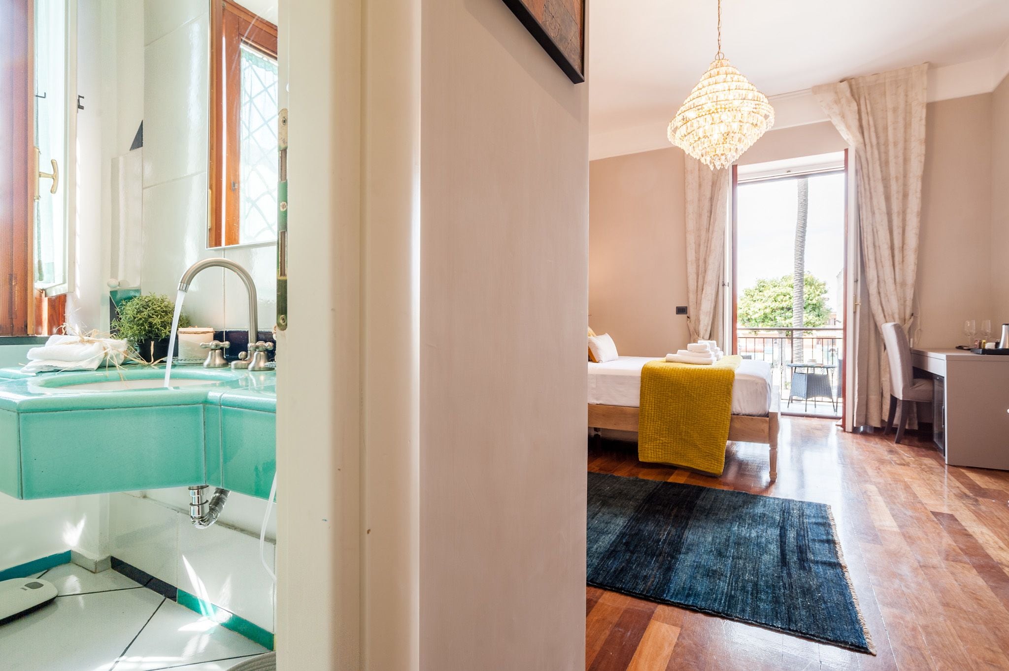 Een moderne badkamer met een grote spiegel, een wastafel en een raam. De kamer heeft een bed met een gele deken en een bureau met een stoel.