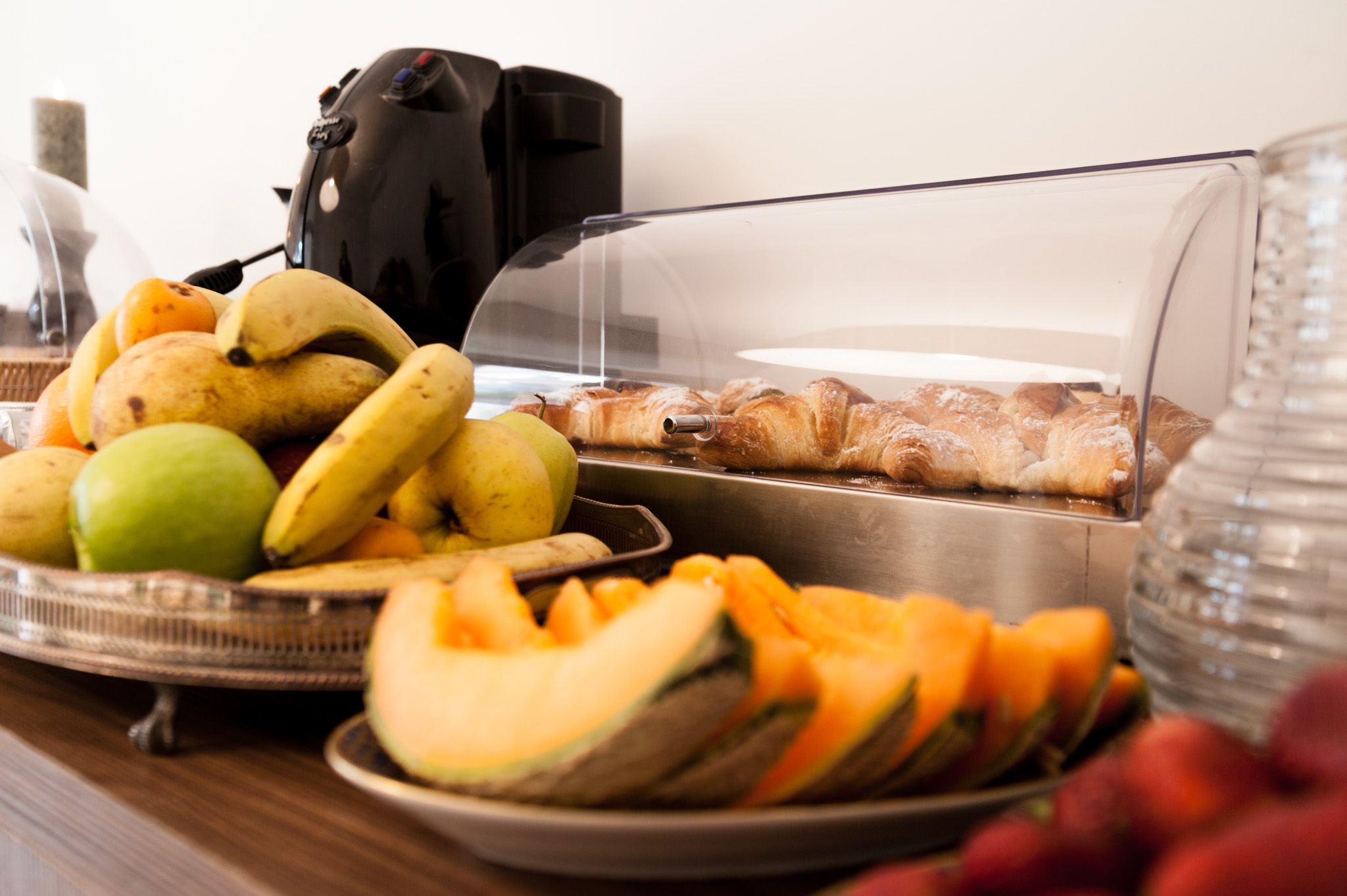 Un buffet de petit-déjeuner proposant des fruits, des viennoiseries et une machine à café.