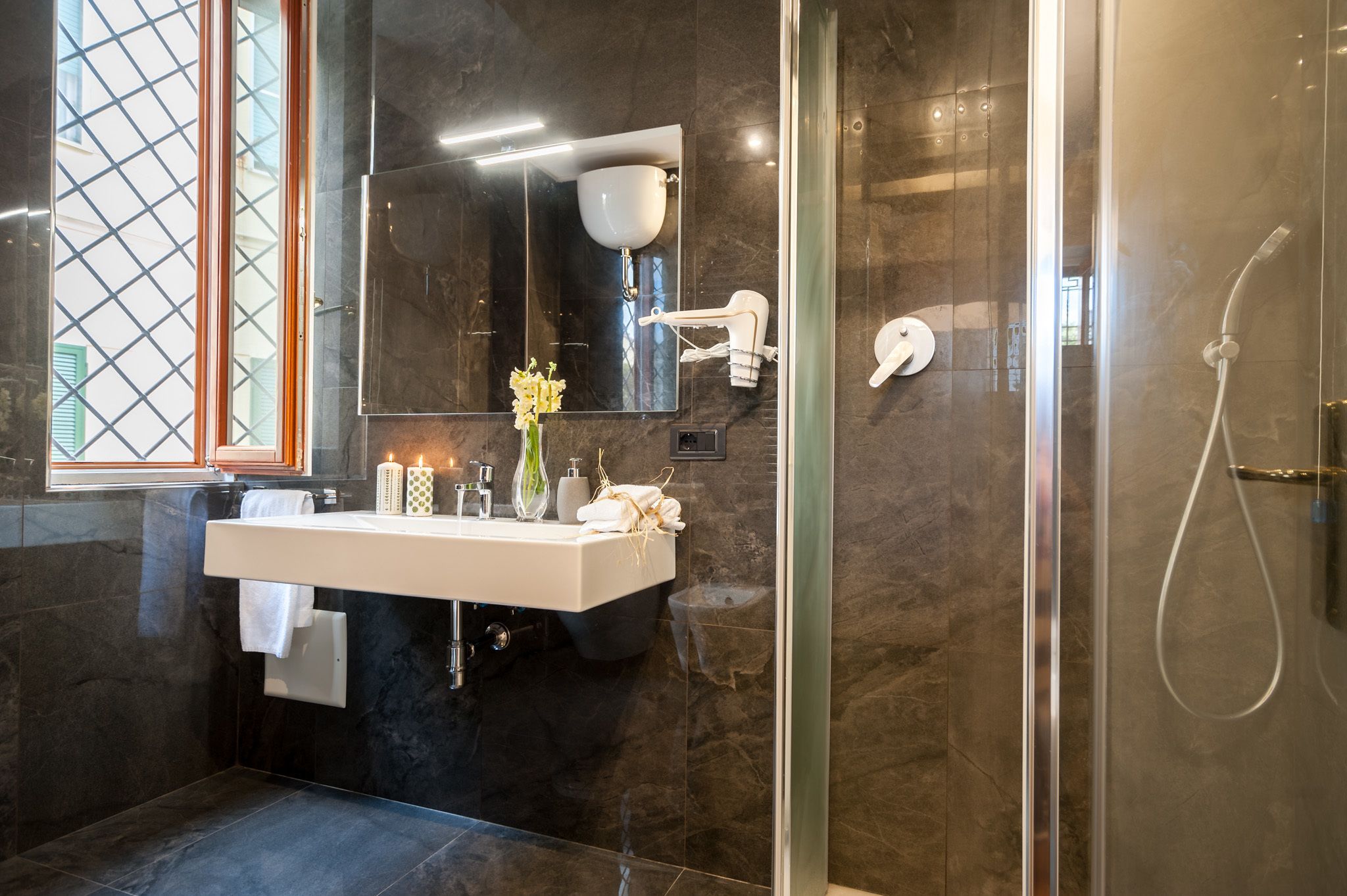 Ein modernes Badezimmer mit einer Duschkabine aus Glas, einem weißen Waschbecken und einem großen Spiegel.
