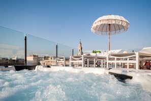 A hot tub area with a large umbrella, a view of a tower, and a glass railing. - Dream house (Pompei)
