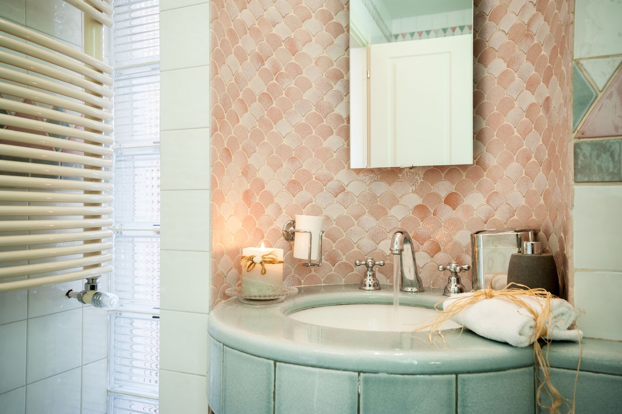 Ein Badezimmer mit runder Waschbecken, Spiegel, Handtuch und Kerze.