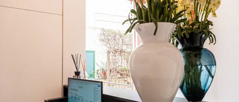 A desk with a computer monitor displaying a webpage, a white vase with flowers, and a blue vase with flowers.