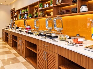 Montaje de bufé con diversos alimentos y utensilios de servicio.