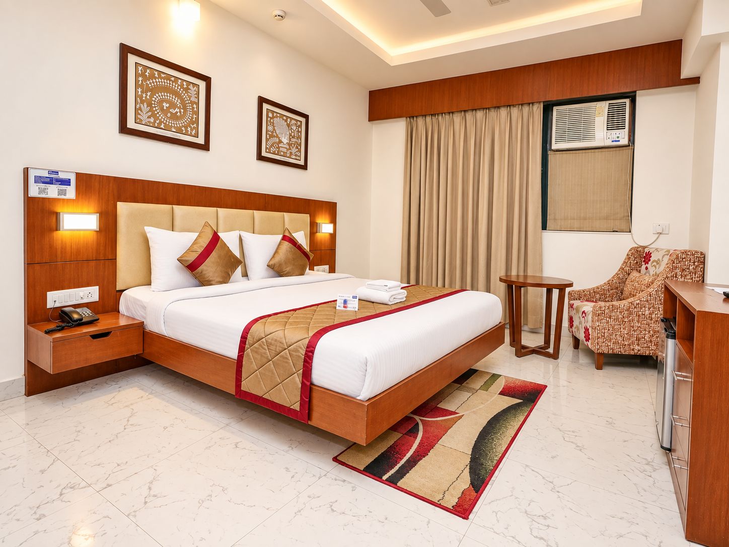 A hotel room with a large bed, a desk, a chair, and a window with curtains.