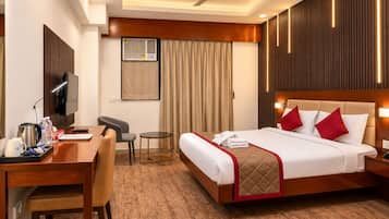 A hotel room with a bed, a desk, a chair, a television, and a ceiling fan.