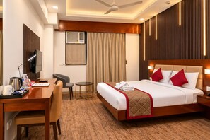 A hotel room with a bed, a desk, a chair, a television, and a ceiling fan. - The Altruist Navi Mumbai Hotel (Navi Mumbai)