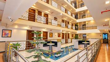 A multi-level hotel lobby with a central pool area, multiple floors, and a modern design.