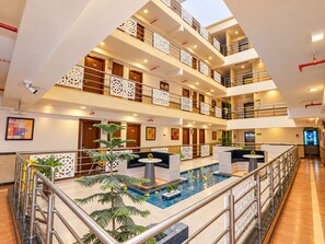 Vestíbulo de hotel de varios niveles con un área de piscina central y un diseño moderno.