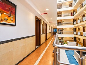 Un pasillo de hotel con piscina, varios pisos y una obra de arte enmarcada en la pared.
