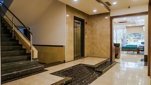 Una hall dell'albergo con una scalinata, un ascensore e una reception con posti a sedere.