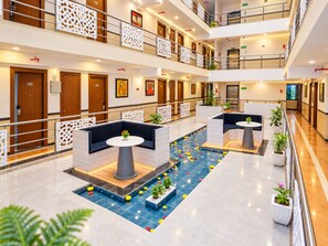 Un hall d’hôtel à plusieurs niveaux, doté d’espaces aménagés avec des sièges, d’une fontaine centrale et d’un design moderne.