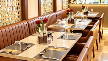 A restaurant with booths and tables, each set with cutlery, glasses, and water bottles.
