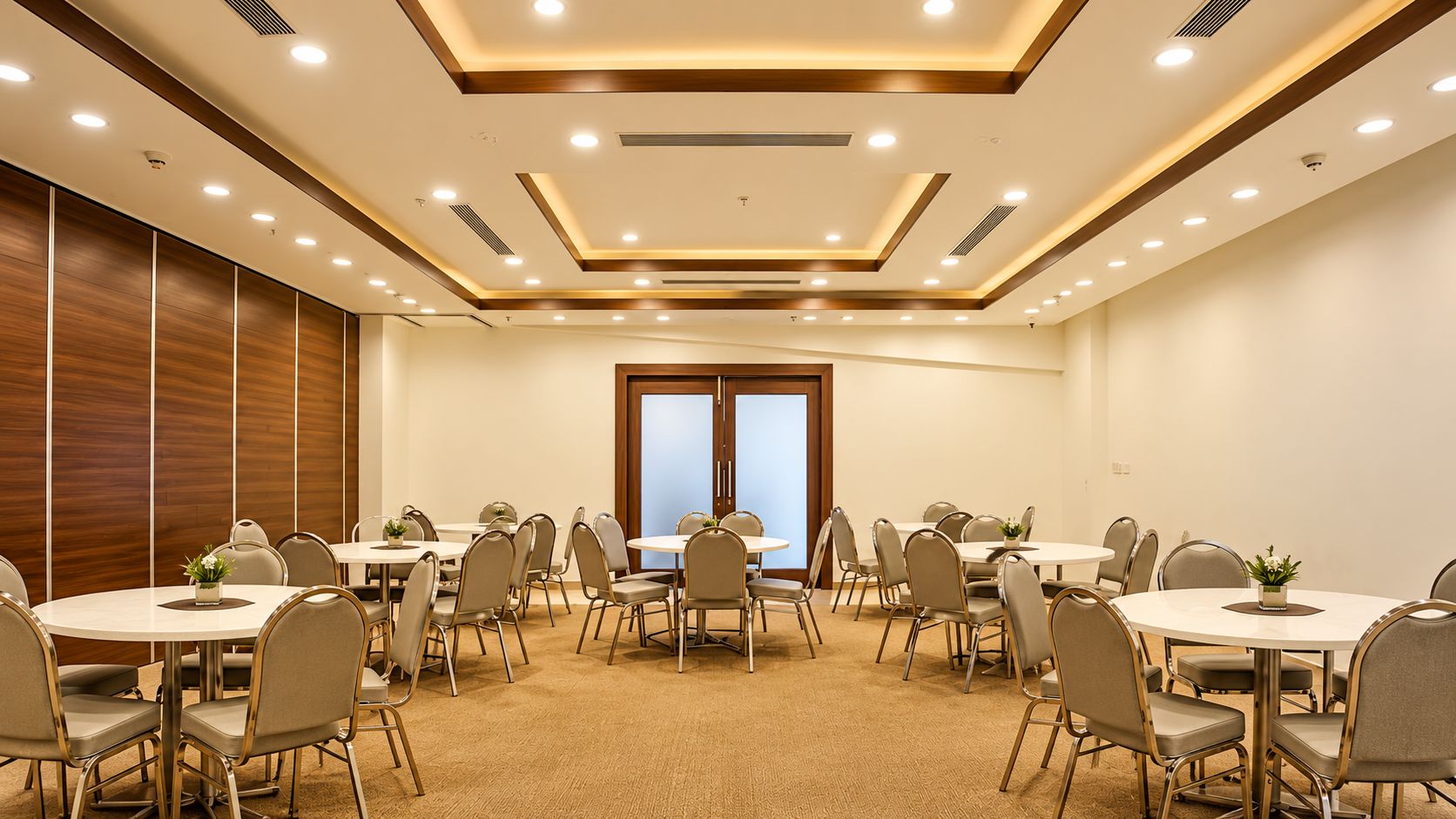 A conference room with multiple round tables, chairs, and a large window.