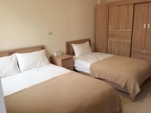 A hotel room with two beds, wooden wardrobe, and a nightstand with a tissue box. - Love Vacation B&B (Jinning)