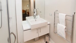 A modern bathroom with a white sink, mirror, and towel rack. - Apartment 25 (Wanaka)