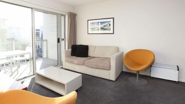 A modern living room with a sofa, a yellow chair, and a white coffee table. - Apartment 25 (Wanaka)