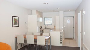 A compact kitchen with a dining area, a small island, and a single chair. - Apartment 25 (Wanaka)