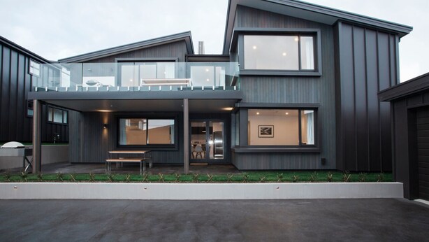 A modern two-story house with a balcony, large windows, and a well-maintained lawn. - Dungarvon Street Apartments (Wanaka)