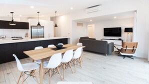 A modern kitchen with a central island, white chairs, and a dining table. - Dungarvon Street Apartments (Wanaka)
