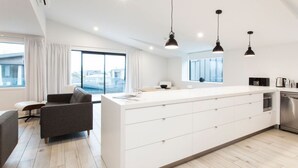 A modern kitchen with a large island, white cabinetry, and pendant lighting. - Dungarvon Street Apartments (Wanaka)