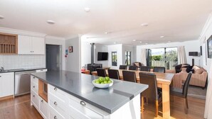 Une cuisine moderne avec des meubles blancs, un plan de travail gris et un coin repas comprenant une table et des chaises en bois.