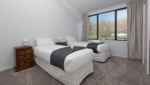Une chambre avec deux lits, une table de chevet et une fenêtre donnant sur l’extérieur.