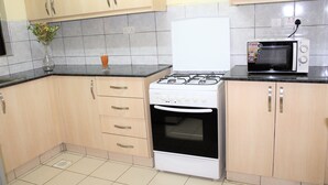 Une cuisine équipée d’une cuisinière, d’un four, d’un four à micro-ondes et de meubles de rangement en bois.