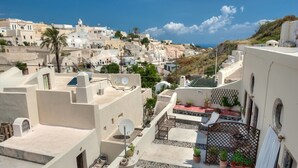 Terraza en la azotea con plantas en macetas, zona de estar y vistas a un pueblo costero.