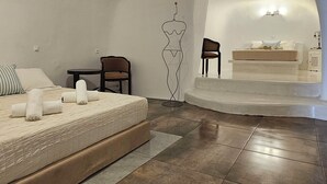 Un dormitorio con cama, una silla, una mesita y un cuadro en la pared.