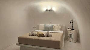 Un dormitorio minimalista con cama, almohadas, una lámpara de noche y una mesita de noche.