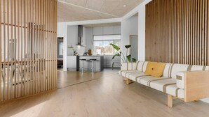 Un salon moderne avec un canapé, une cloison en bois et une cuisine en arrière-plan.