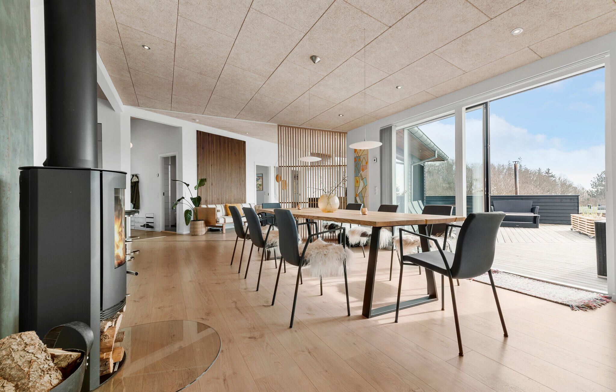 Un espace repas moderne avec une grande table, des chaises et un poêle à bois.