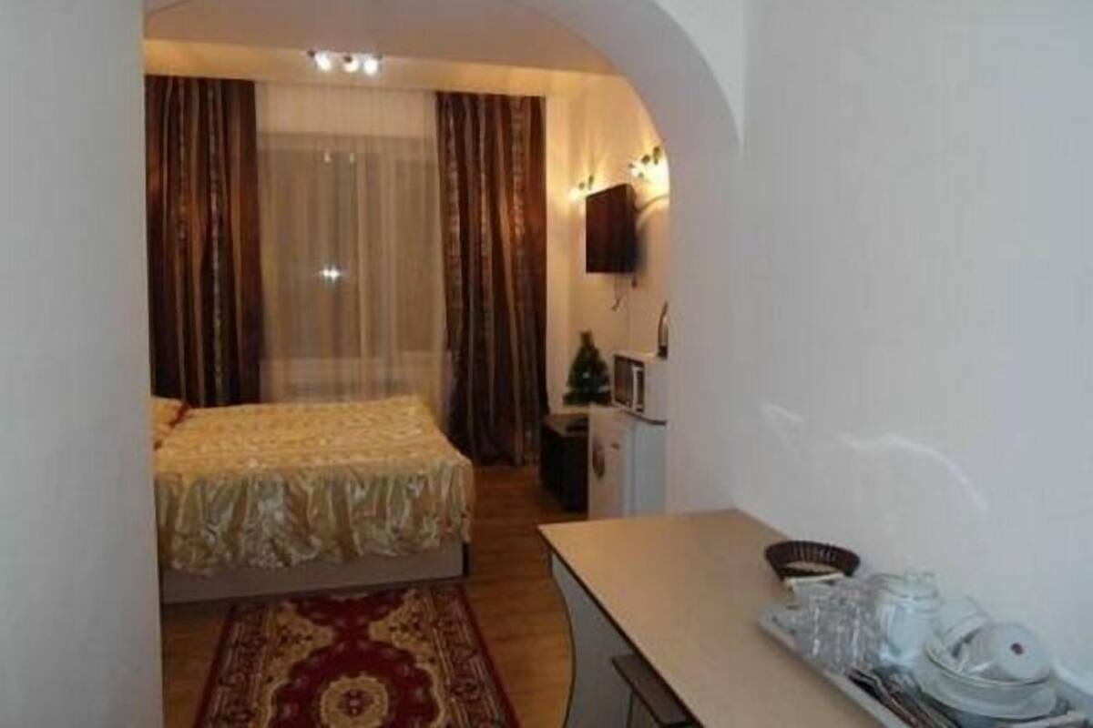 A small, cozy room with a bed, a desk, a chair, a TV, and a small Christmas tree.