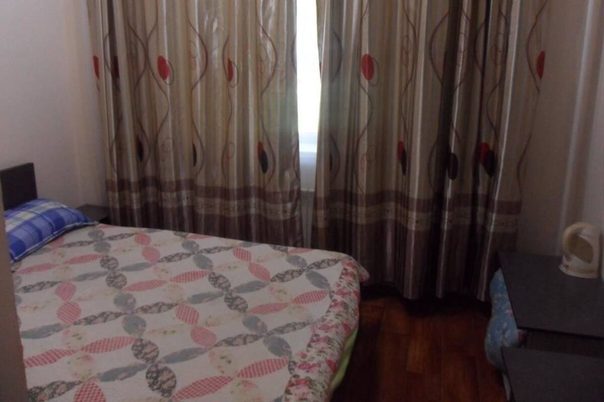 A bedroom with a bed, curtains, and a small table.