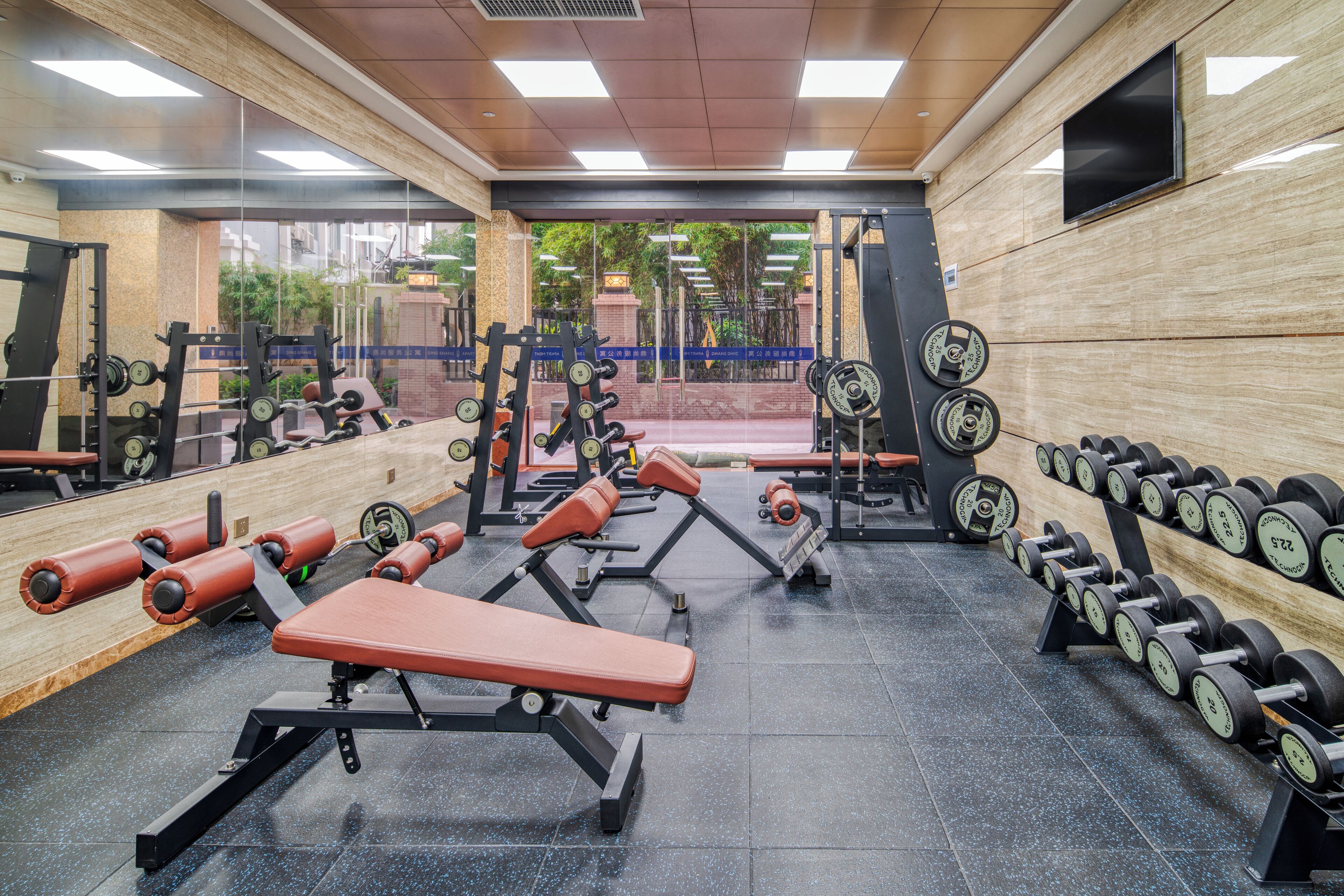 A gym with weightlifting equipment, benches, and a mirrored wall.