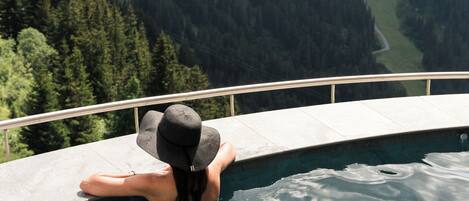 Una persona descansando en una piscina con un paisaje montañoso al fondo.