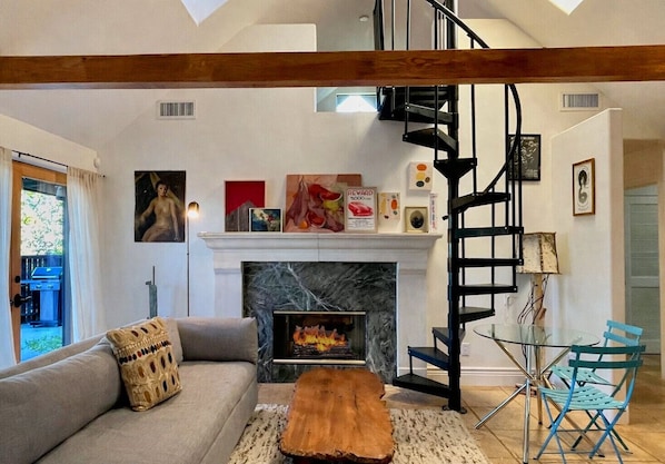 Uma sala de estar moderna com lareira, um sofá, uma mesa de centro e uma escada em espiral.