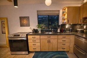 Uma cozinha moderna com forno embutido, pia, armários de madeira e janela com vista para árvores.