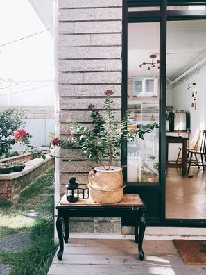 Une terrasse avec une table, un pot de fleurs et une lanterne suspendue.