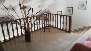 Una escalera con baranda de madera, una planta en maceta y cuadros en las paredes.